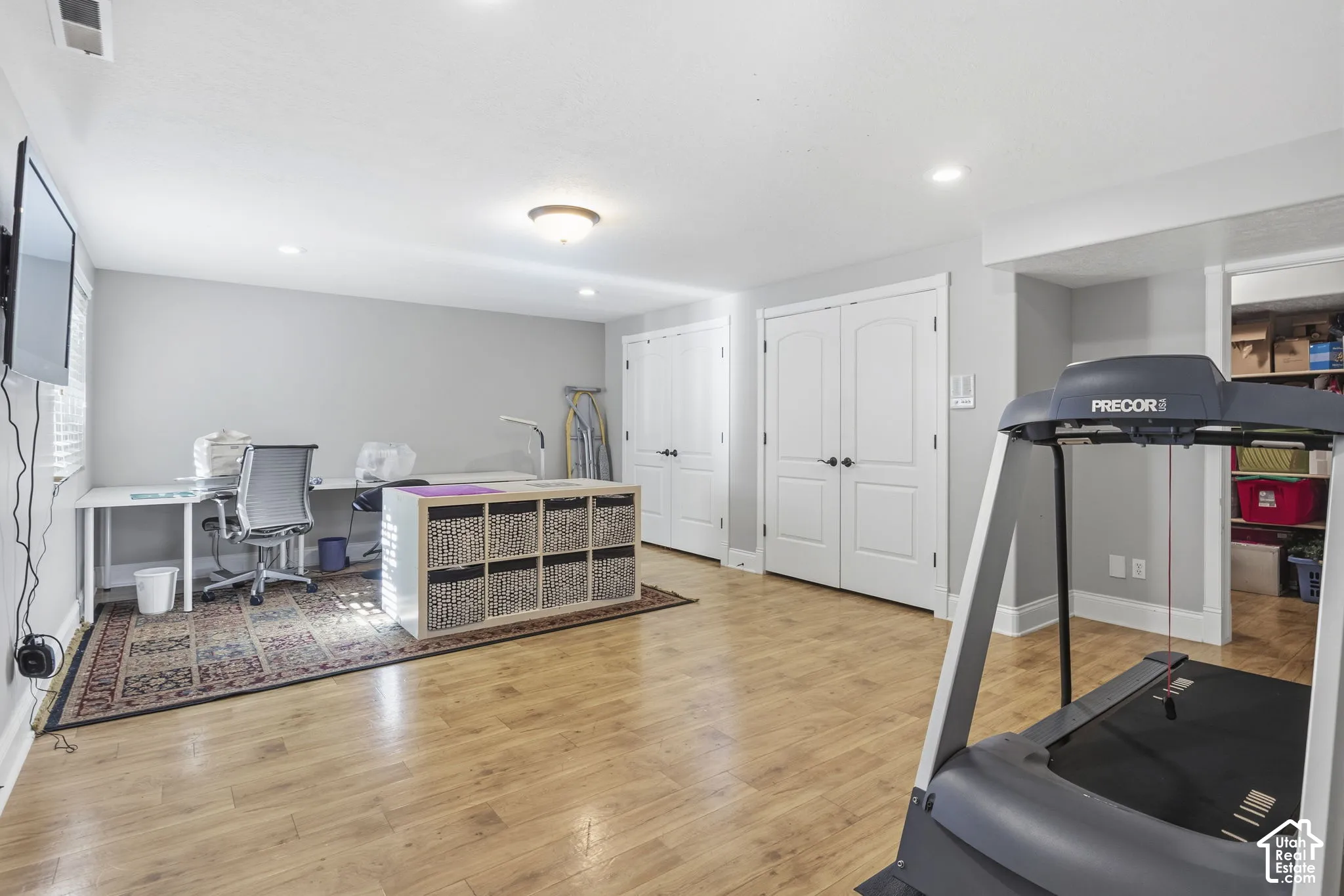 Multipurpose space featuring wood-finish flooring, recessed lighting, and dual sets of white paneled interior doors