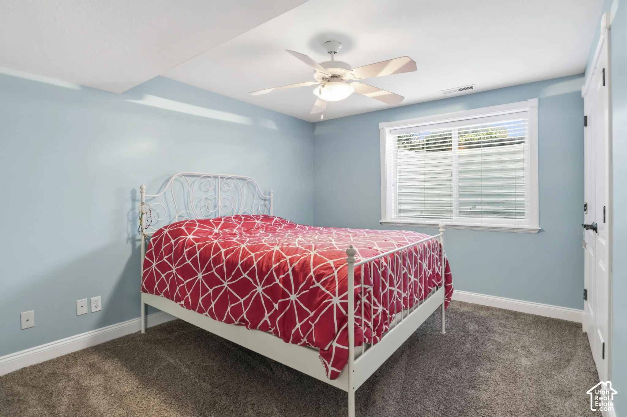 Room featuring wall-to-wall carpeting, a white ceiling fan with integrated lighting, a sliding window with horizontal blinds, and a paneled closet door