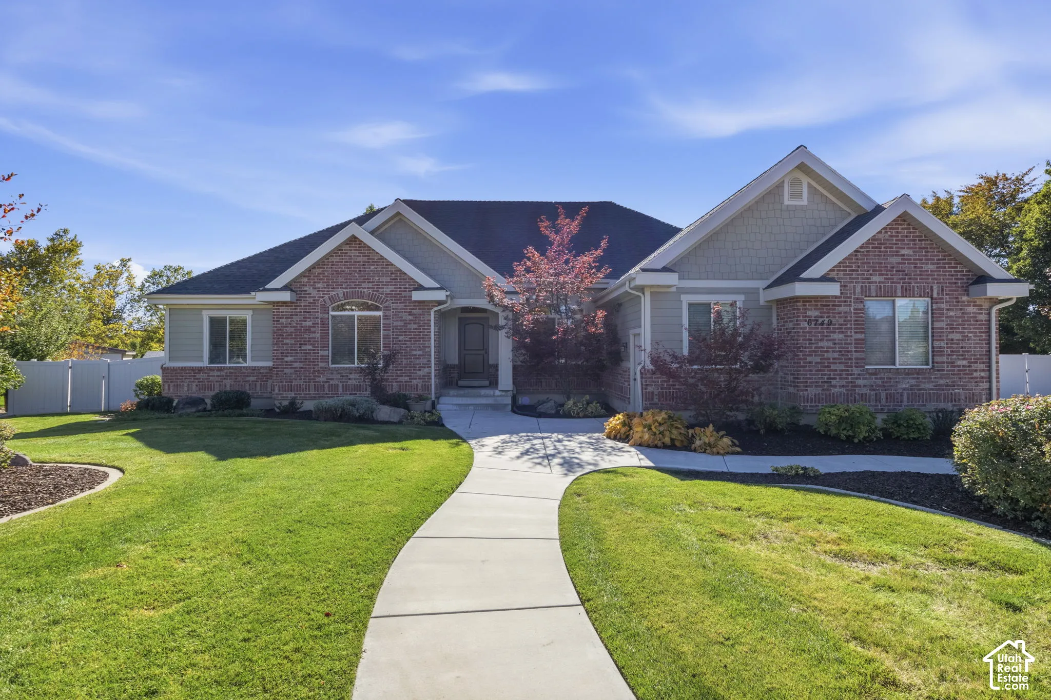 Single-story residence featuring a brick and shingle exterior, multi-gabled roofline, concrete walkway, and landscaped front yard