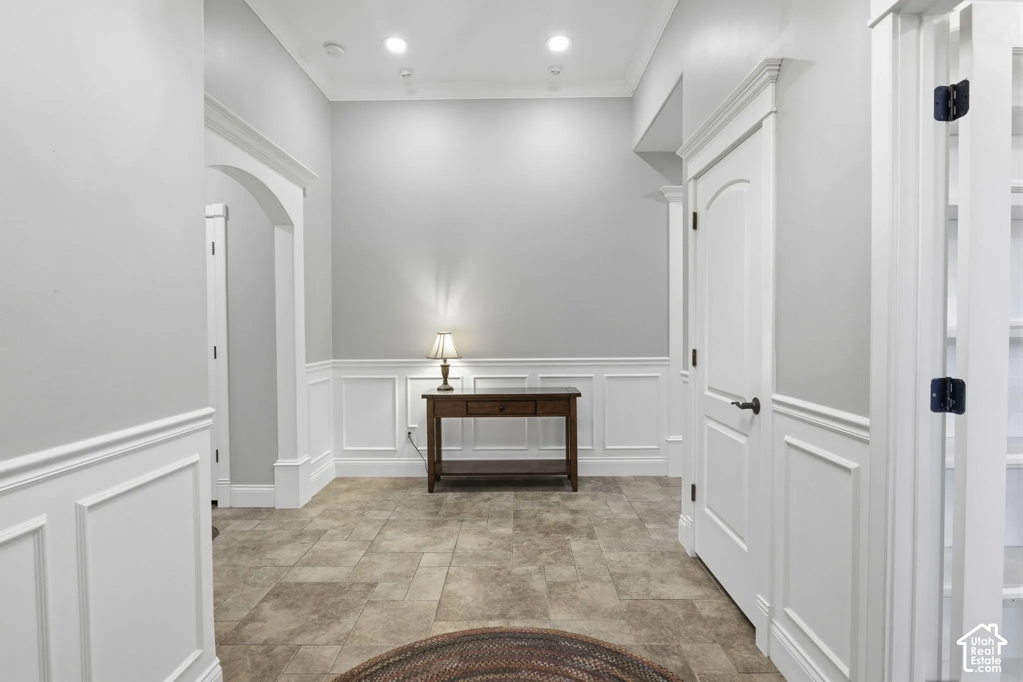 Foyer featuring tile flooring, wainscoting, arched openings, recessed ceiling lighting, and solid-core interior doors