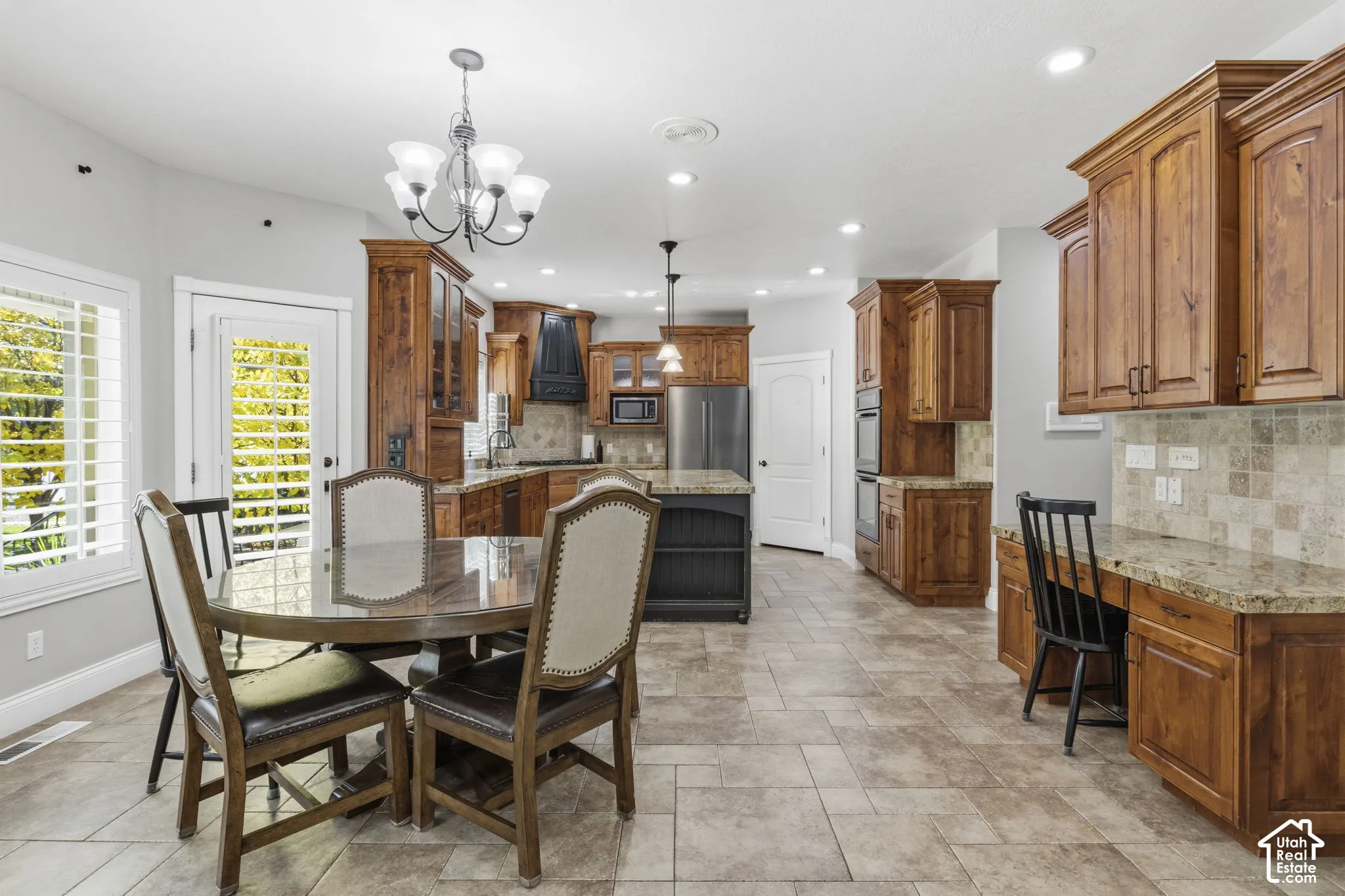 Kitchen featuring stained wood cabinetry, stone countertops, integrated stainless steel appliances, tile flooring, and a stone tile backsplash