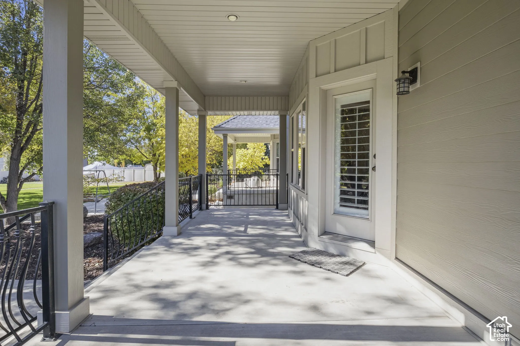 Covered porch featuring concrete flooring, horizontal lap siding, recessed ceiling lighting, and black metal railings