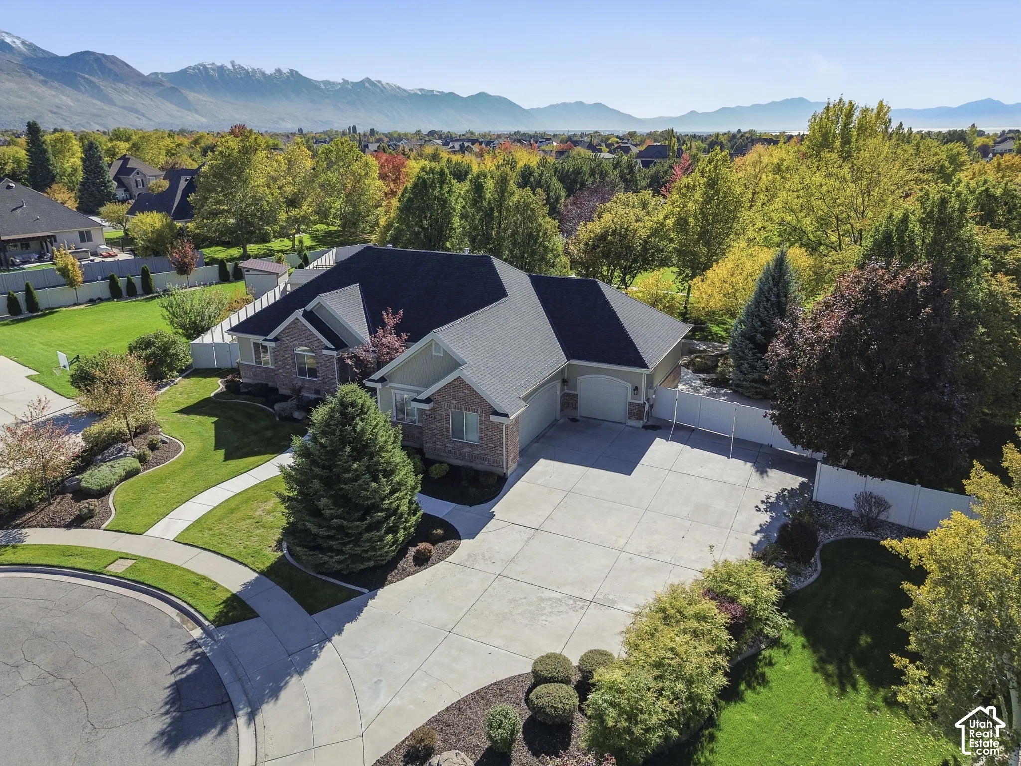 Multi-level brick and siding exterior featuring an attached multi-car garage, concrete driveway, and mountain backdrop