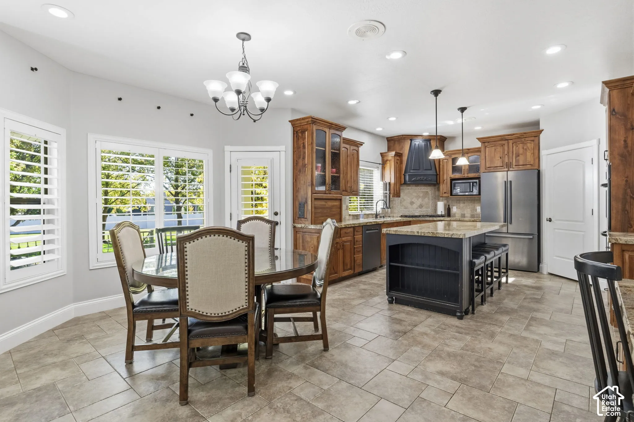 Kitchen featuring natural wood cabinetry, a contrasting central island with built-in shelving, stone-finish countertops, recessed lighting, and tile flooring