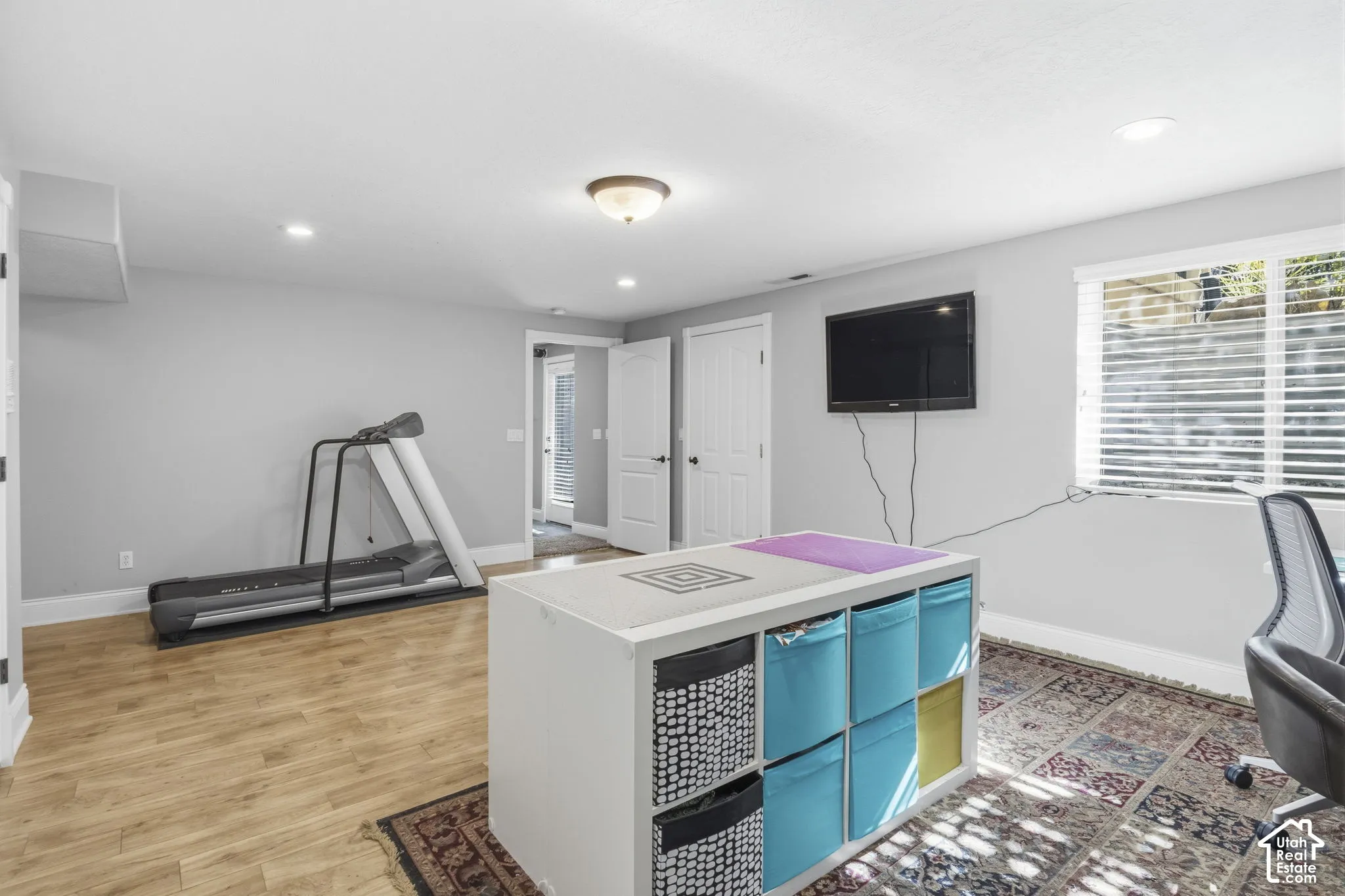Interior space featuring neutral wall paint, wood-finish flooring, recessed lighting, and a window with horizontal blinds