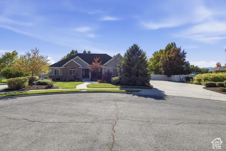 Single-story residence featuring a brick and siding exterior, multi-gabled roofline, concrete driveway, and established landscaping