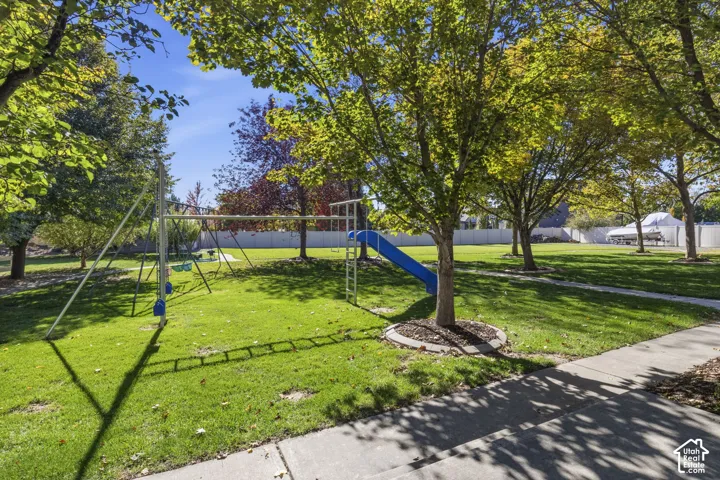 Expansive backyard featuring mature trees, manicured lawn, concrete walkways, and perimeter fencing