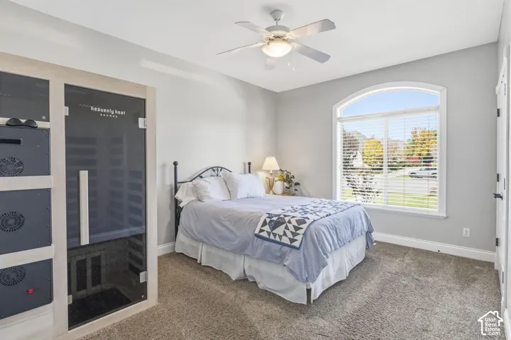 Arched window with casing, ceiling fan with integrated light fixture, and neutral carpeting