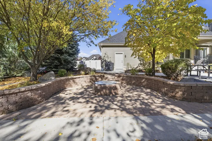 Paver patio featuring a built-in stone fire pit and a tiered segmental retaining wall