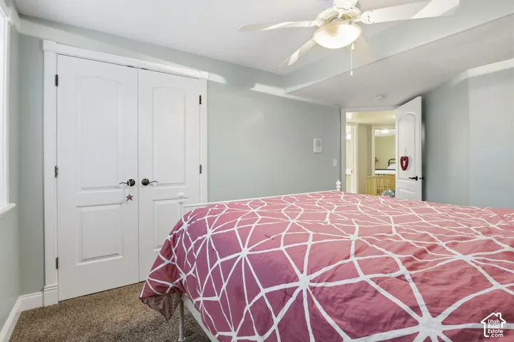 Room featuring neutral wall tones, wall-to-wall carpeting, white paneled double-door closet, and a ceiling-mounted light fixture with integrated fan
