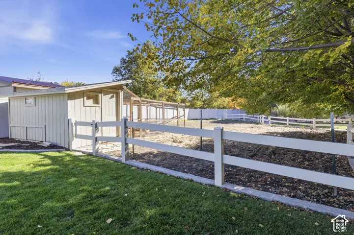 Fenced backyard featuring a storage shed, wood-post and rail fencing, and mature trees