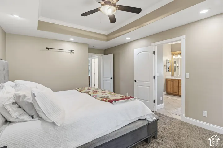 Tray ceiling featuring recessed lighting and a central ceiling fan, neutral wall tones, and interior doors with oil-rubbed bronze hardware