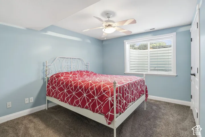 Room featuring wall-to-wall carpeting, a white ceiling fan with integrated lighting, a sliding window with horizontal blinds, and a paneled closet door