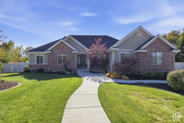 Single-story residence featuring a brick and shingle exterior, multi-gabled roofline, concrete walkway, and landscaped front yard