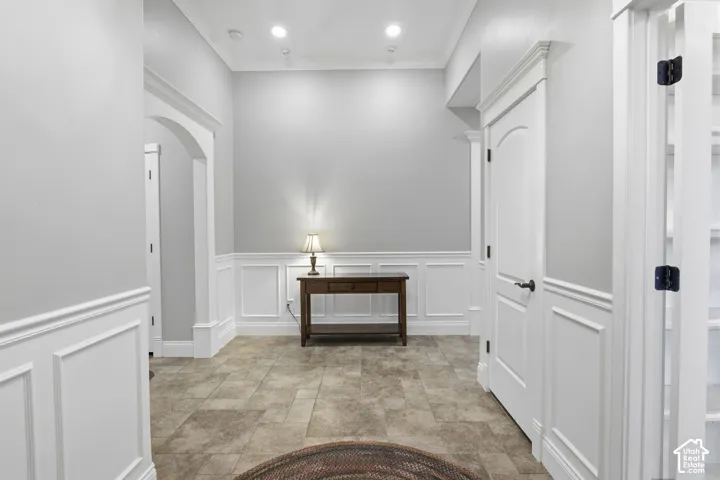 Foyer featuring tile flooring, wainscoting, arched openings, recessed ceiling lighting, and solid-core interior doors