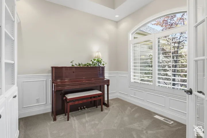 Room featuring a vaulted ceiling, arched window with interior shutters, wainscoting, and built-in white cabinetry