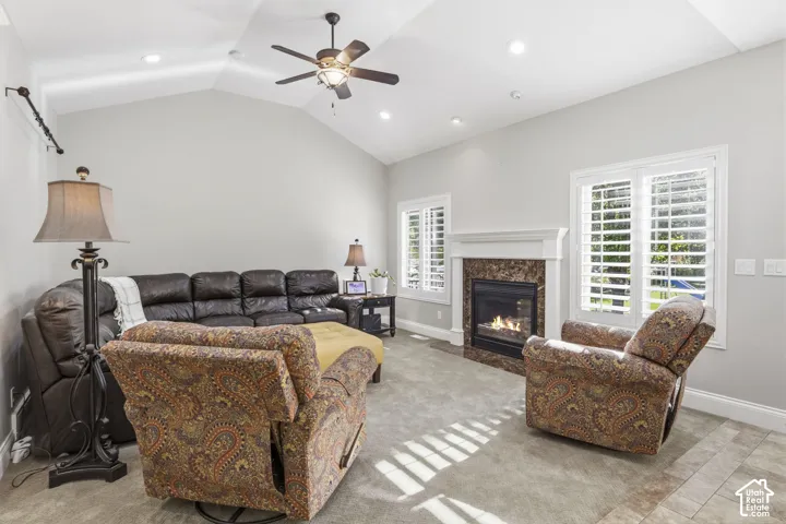 Vaulted ceilings, fireplace with stone-finish surround and custom mantel, recessed lighting, ceiling fan, and plantation shutters