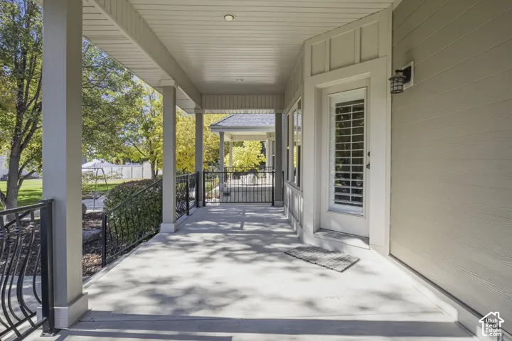 Covered porch featuring concrete flooring, horizontal lap siding, recessed ceiling lighting, and black metal railings