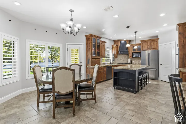 Kitchen featuring natural wood cabinetry, a contrasting central island with built-in shelving, stone-finish countertops, recessed lighting, and tile flooring