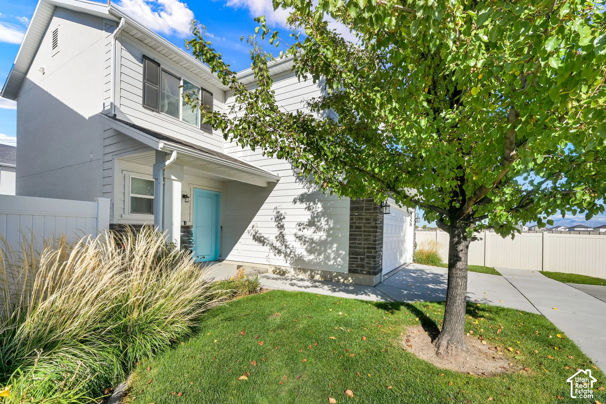 Two-story residence featuring horizontal lap siding, stone veneer accents, an attached two-car garage, concrete driveway, and a front lawn with mature landscaping