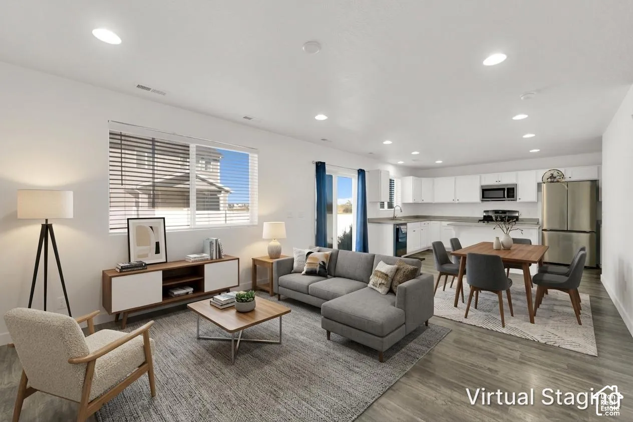 Open-concept interior featuring wood-finish flooring, recessed lighting, and a kitchen equipped with white cabinetry and stainless steel appliances