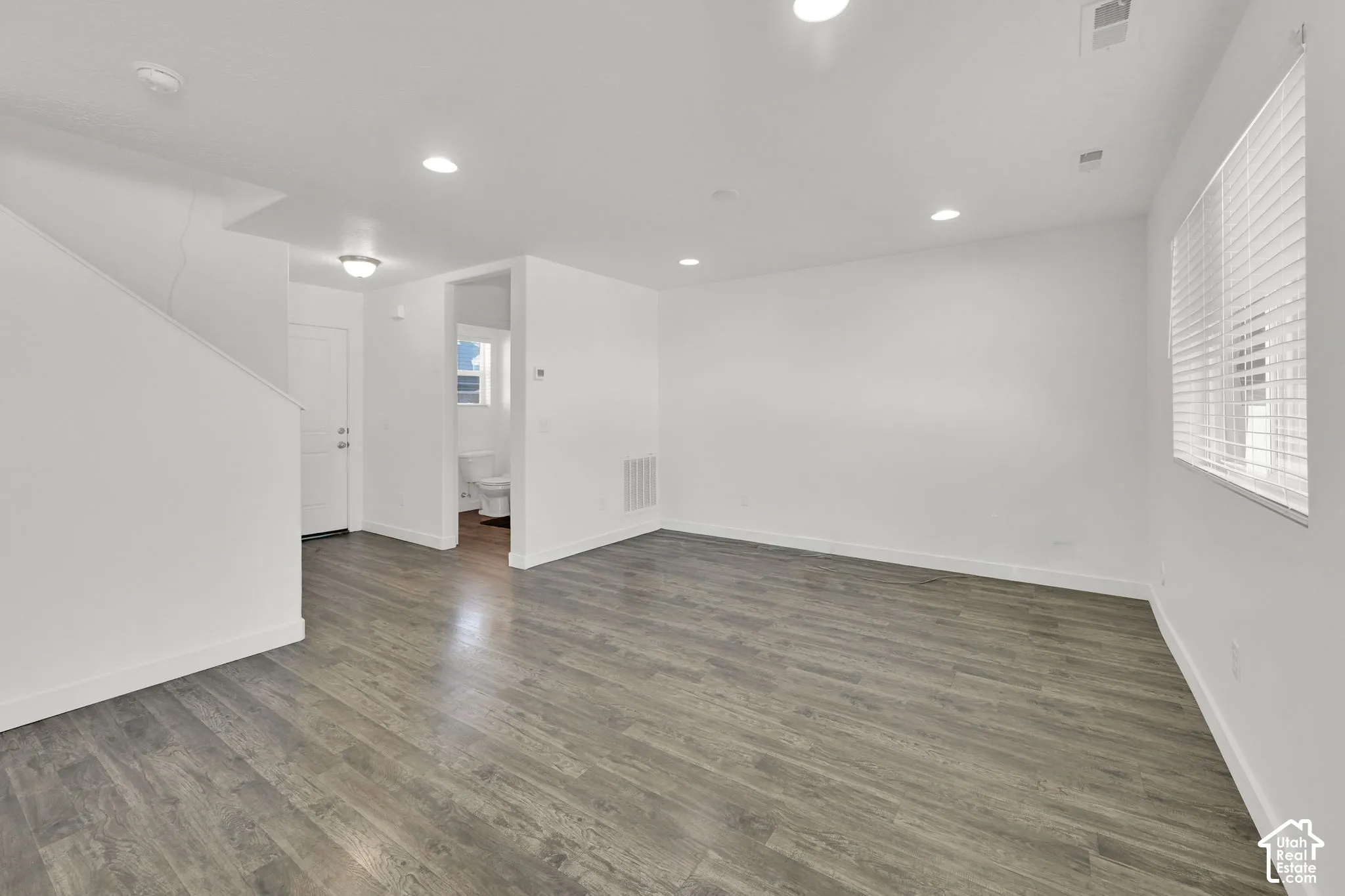 Open-concept area featuring wood-finish flooring, recessed lighting, and horizontal window blinds