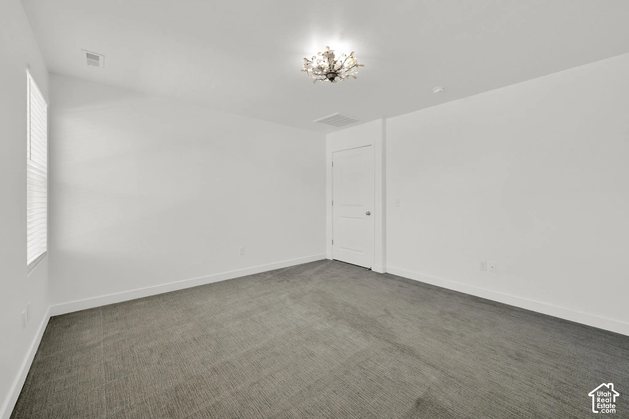 Neutral-toned carpeted flooring, multi-panel interior door, and a decorative flush-mount ceiling light fixture