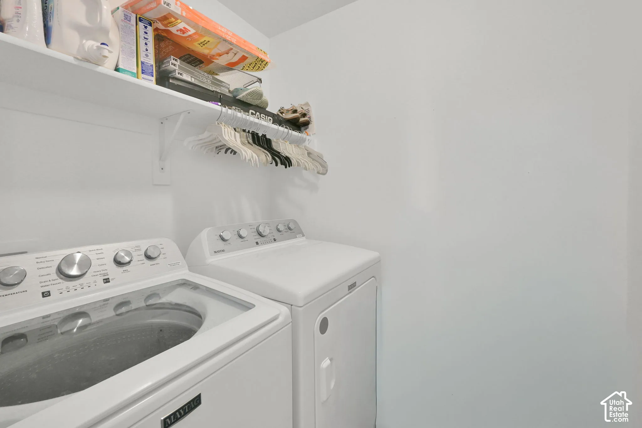 Laundry area featuring a top-load washer, a front-loading dryer, and overhead wire shelving with a built-in hanging rod