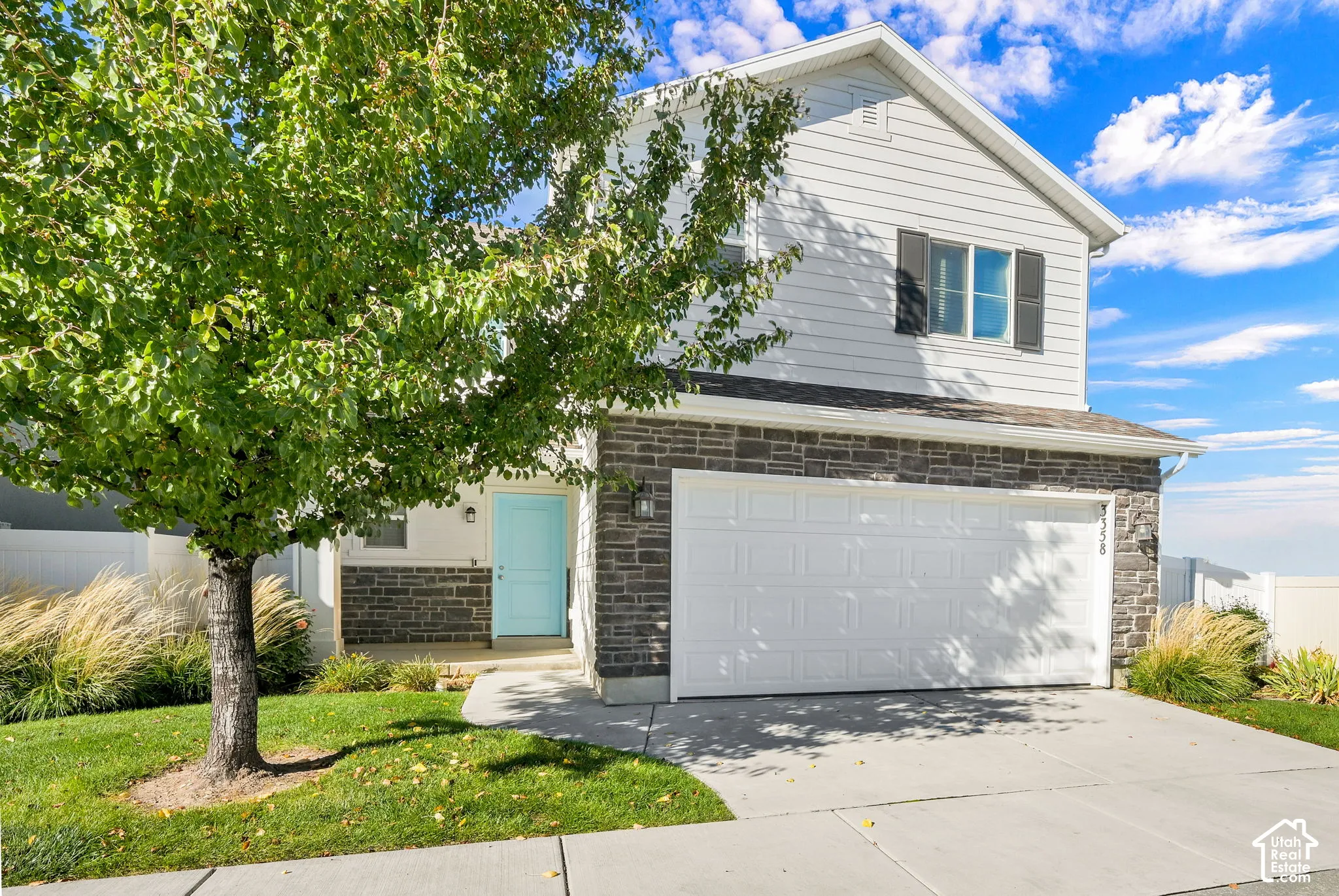 Two-story exterior featuring stone veneer accents, horizontal siding, attached two-car garage, and a solid-colored entry door