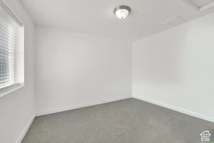 Neutral-toned interior space featuring wall-to-wall carpeting, white walls, and a ceiling-mounted flush-mount light fixture