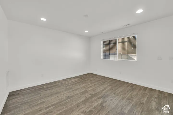 Neutral-toned interior space featuring wood-finish flooring, recessed lighting, and a window with horizontal blinds