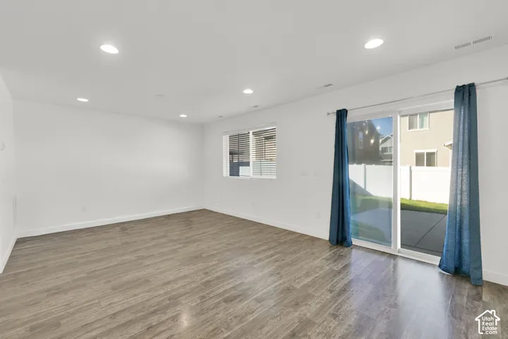 Spacious interior featuring wood-finish flooring, recessed lighting, and sliding glass doors with direct access to a concrete patio