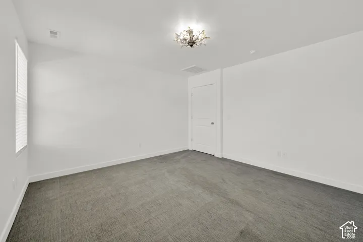 Neutral-toned carpeted flooring, multi-panel interior door, and a decorative flush-mount ceiling light fixture