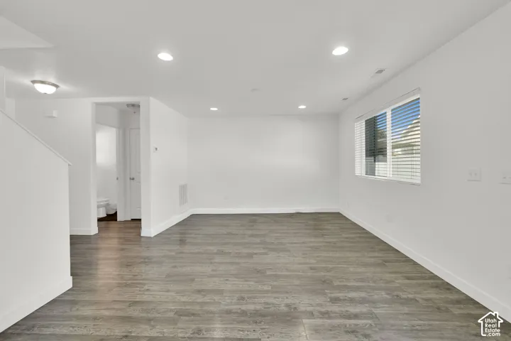 Neutral-toned interior space featuring wood-finish flooring, recessed lighting, and a window with horizontal blinds