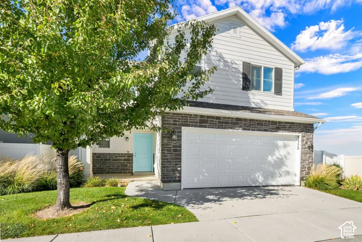 Two-story exterior featuring stone veneer accents, horizontal siding, attached two-car garage, and a solid-colored entry door