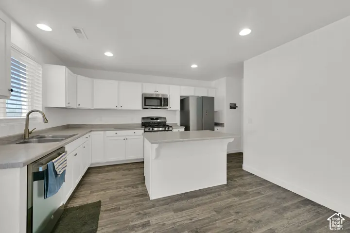 Kitchen featuring white cabinetry, wood-finish flooring, a central island, and recessed ceiling lighting
