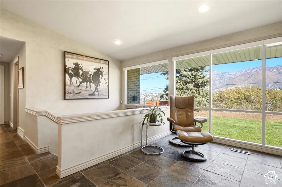 Floor-to-ceiling windows featuring mountain scenery, stone-tile flooring, and recessed ceiling lighting