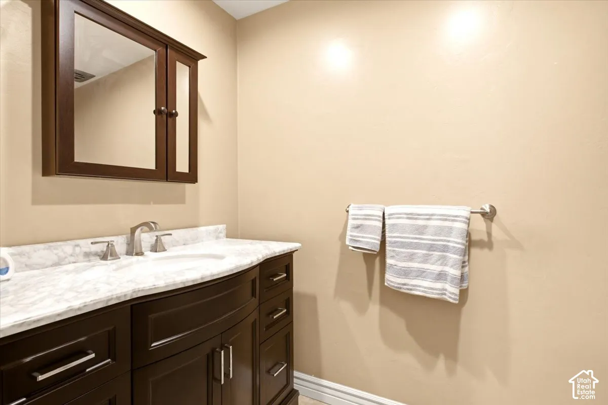 Dark wood vanity with a white stone countertop, integrated sink, metal hardware, and matching wall-mounted medicine cabinet