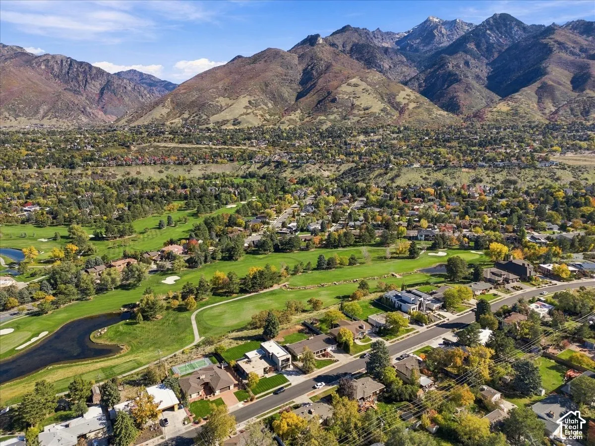 Aerial perspective featuring a prominent mountain backdrop, expansive manicured grounds, and immediate proximity to a golf course