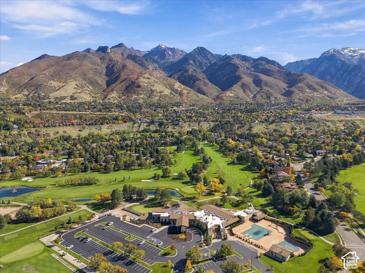 Aerial perspective of property grounds featuring a swimming pool, multiple water features, sprawling green space, and a mountainous backdrop