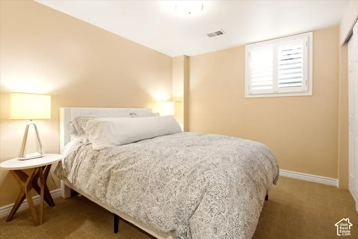 Interior room featuring neutral-toned wall paint, textile carpeting, a recessed window with plantation shutters, and white paneled door