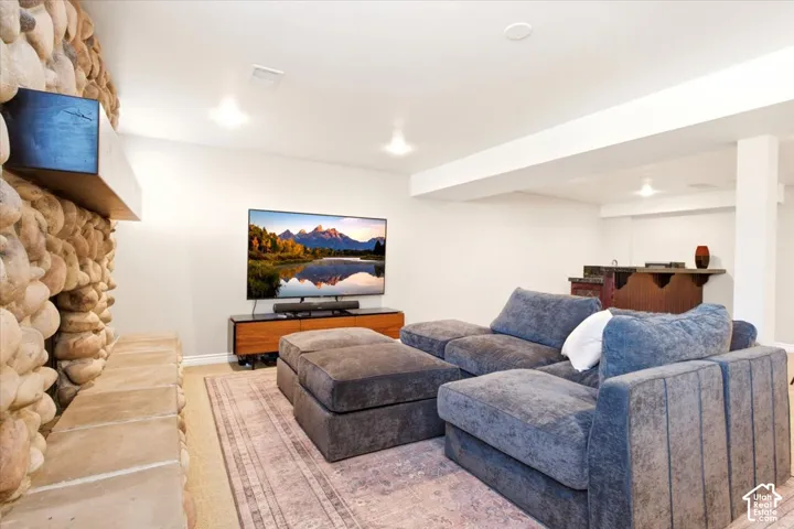 Floor-to-ceiling river rock fireplace with a wood mantle, built-in wet bar, and recessed lighting