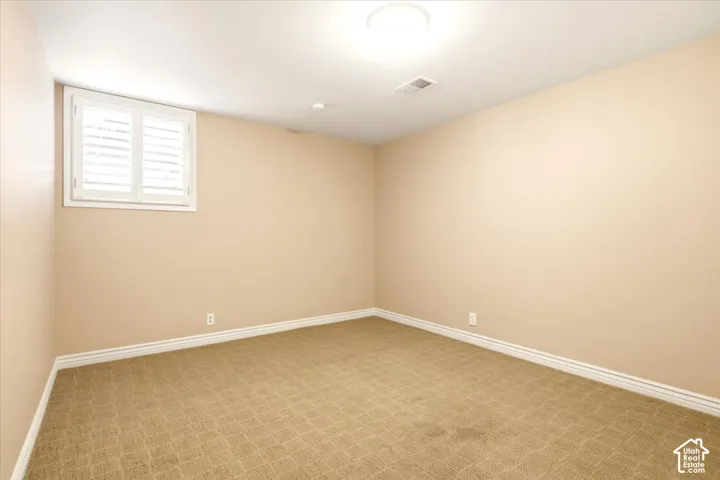 Interior room featuring neutral wall paint, wall-to-wall carpeting, and a window fitted with white plantation shutters
