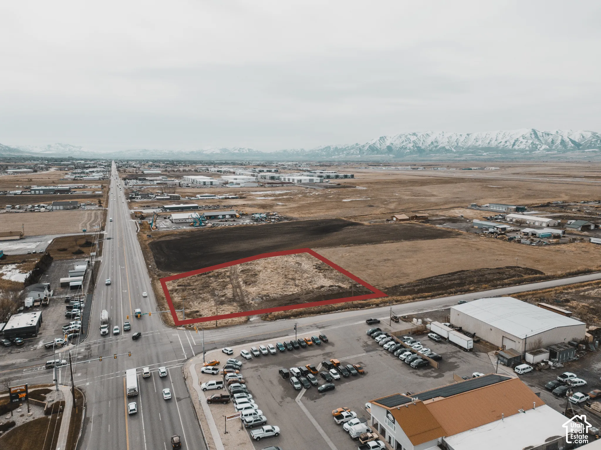 Expansive undeveloped land parcel situated with direct frontage to a major thoroughfare, featuring prominent mountain backdrops