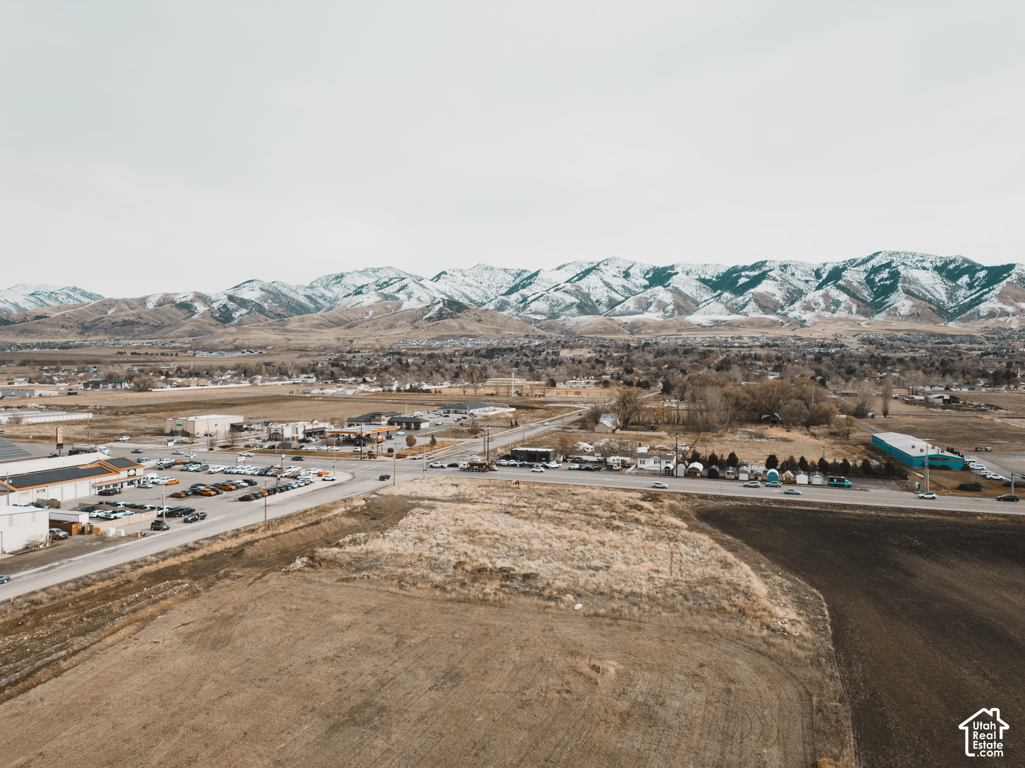 Aerial perspective of open terrain featuring expansive mountain backdrops and proximity to established roadway infrastructure