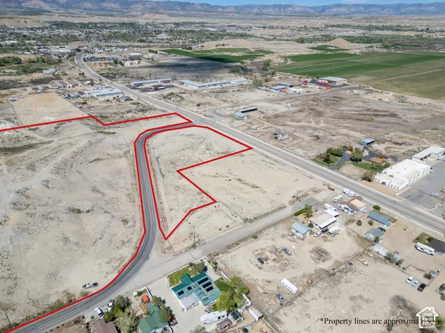 Aerial view of unimproved land parcel featuring paved street access, corner lot positioning, and mountain terrain backdrop