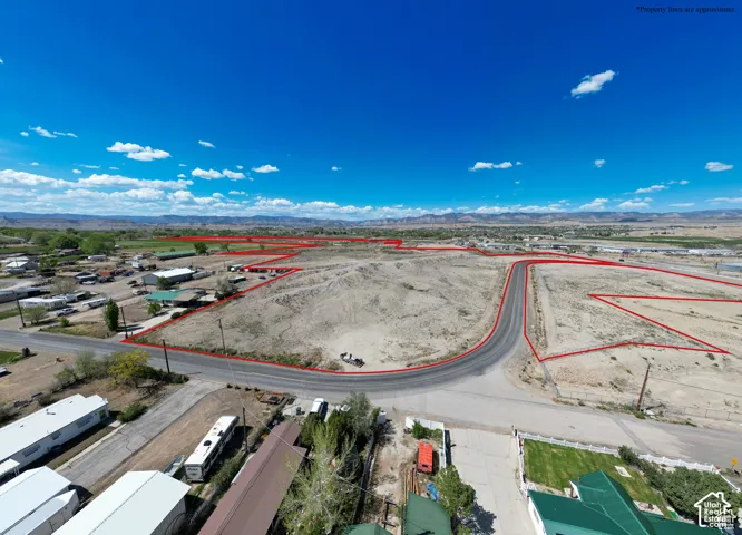 Expansive plot of land featuring paved road access, leveled terrain, and mountain backdrop