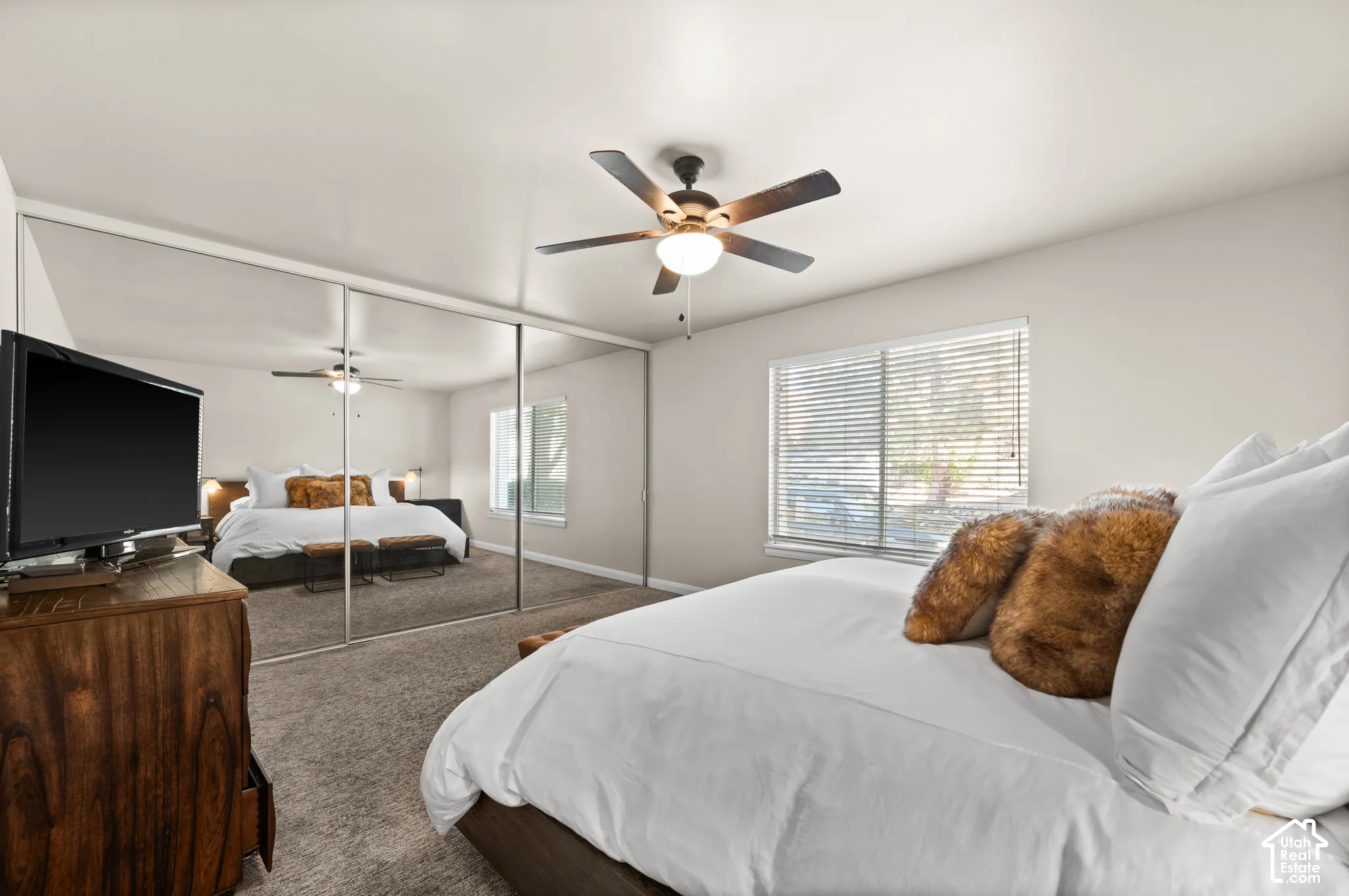 Wall-to-wall mirrored sliding closet doors, wall-to-wall carpeting, ceiling fan with integrated lighting, and window blinds