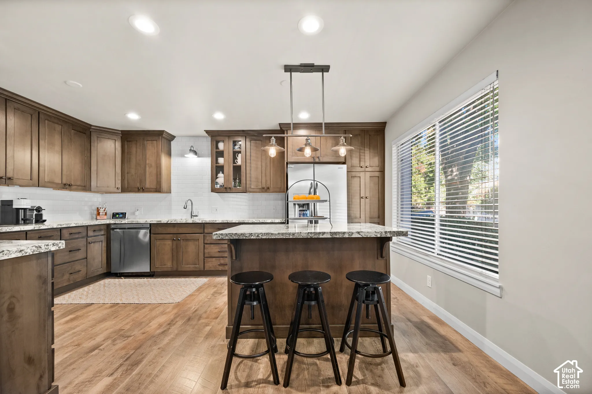 Kitchen featuring wood cabinetry, stone countertops, wood-finish flooring, recessed lighting, and a pendant-lit center island