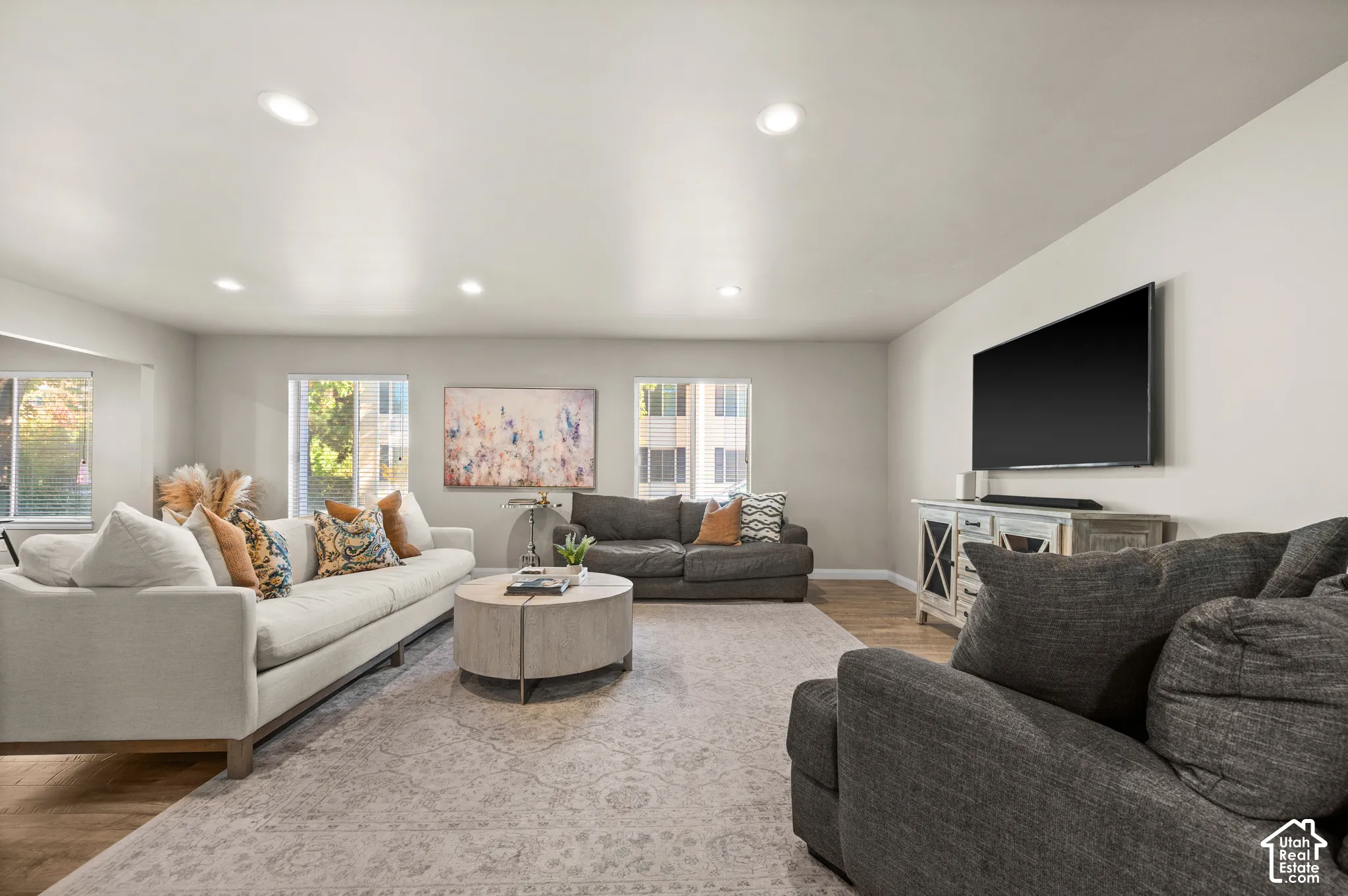 Living area featuring recessed ceiling lighting, light-toned wood-finish flooring, and multiple dual-pane windows